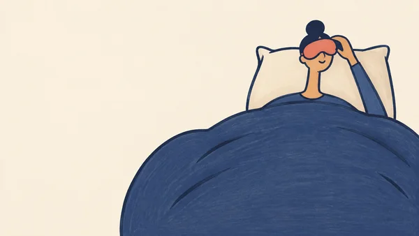 A person sits tucked beneath an oversized indigo duvet, raising an arm toward a coral sleep mask over their eyes.