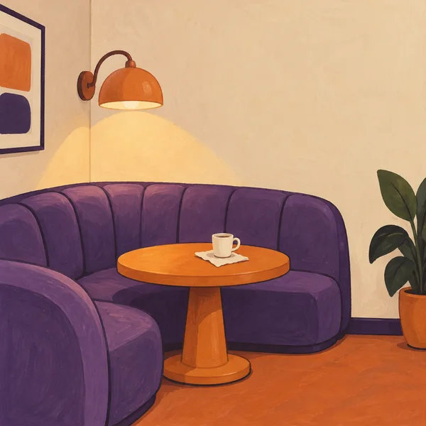 A violet upholstered banquette curves around a corner beside a round orange pedestal table holding a cream cup and pale napkin.