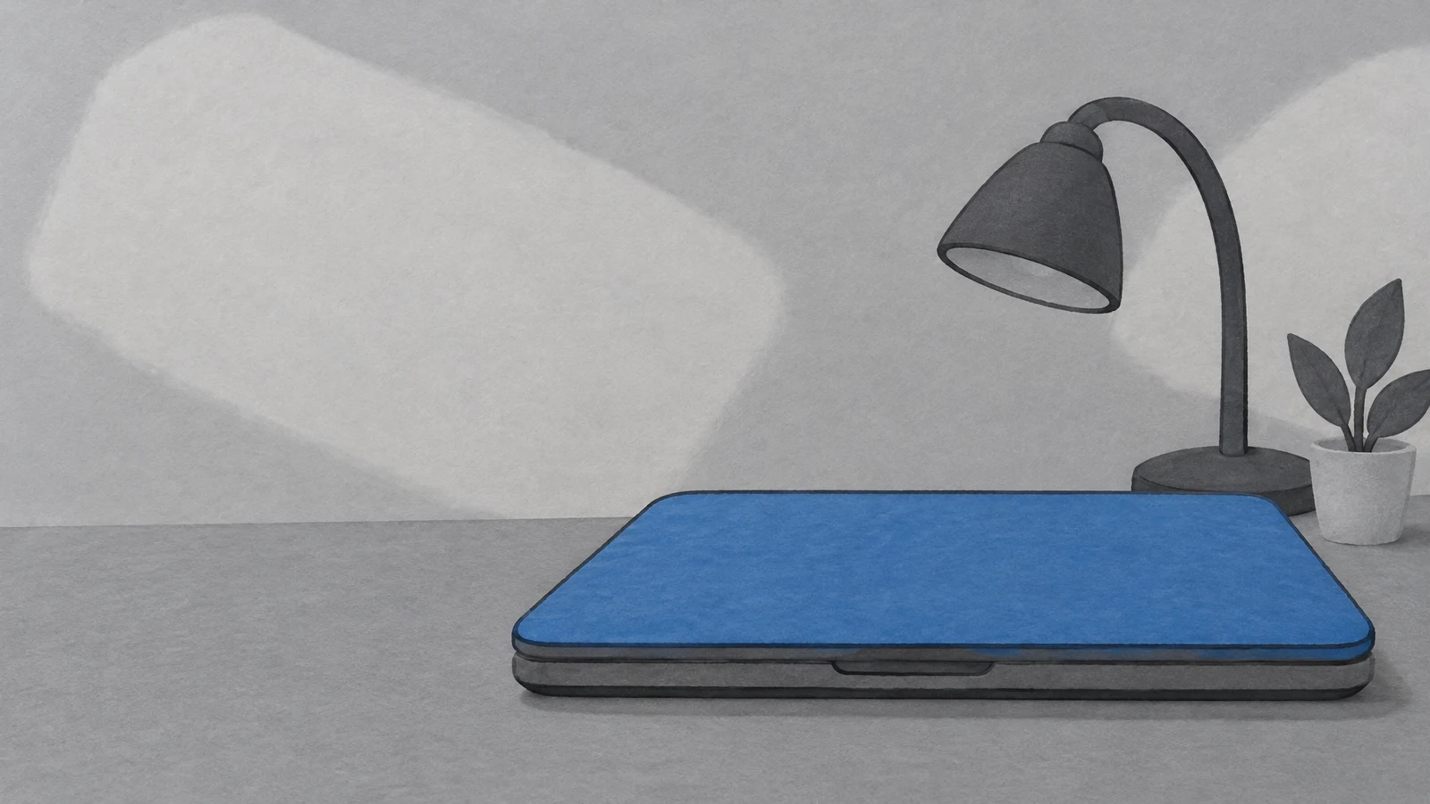 A wide, closed blue-lidded laptop rests on a silver-gray desktop, with a dark task lamp and a small potted plant behind it against a softly mottled gray…