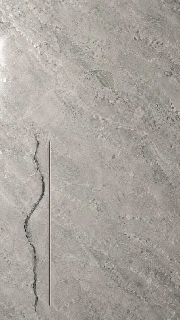 Overhead view of pale grey limestone with a dark, wavering vertical vein and a parallel straight narrow groove in the lower-left area; mottled mineral texture…