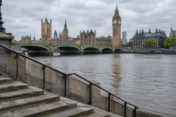 Stone steps and a dark metal railing descend toward the Thames in the foreground, with Westminster Bridge, the Palace of Westminster and Elizabeth Tower across…