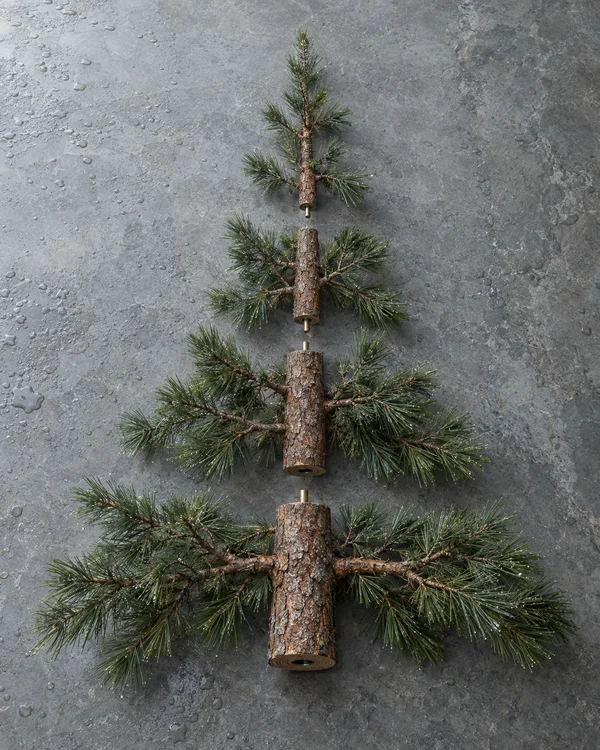 Four bark-covered pine sections lie in a vertical line on a wet gray stone surface, with small brass connectors visible between the sections and a dark socket…