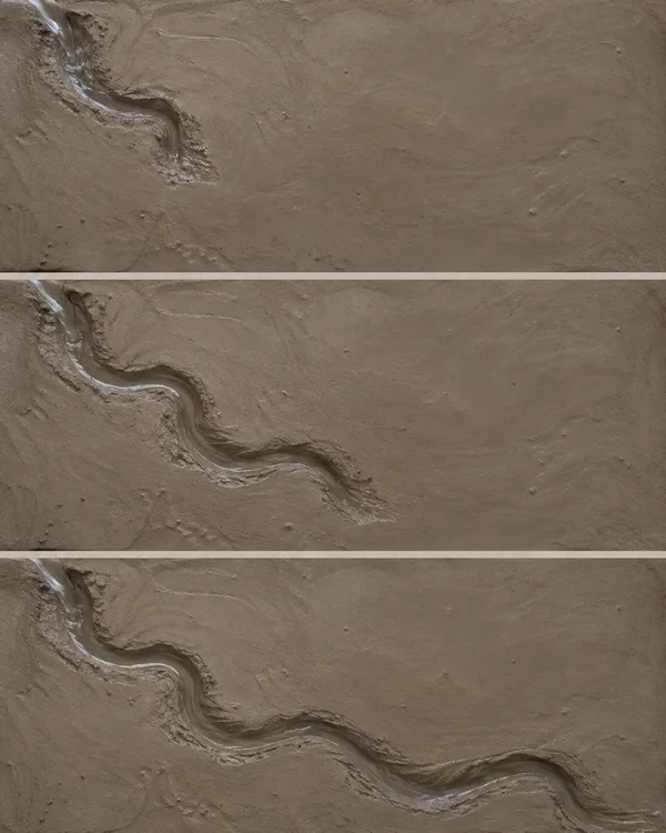 Three overhead views of damp grey-brown clay stacked vertically, with a glossy sinuous water channel growing longer from the upper left toward the lower right…