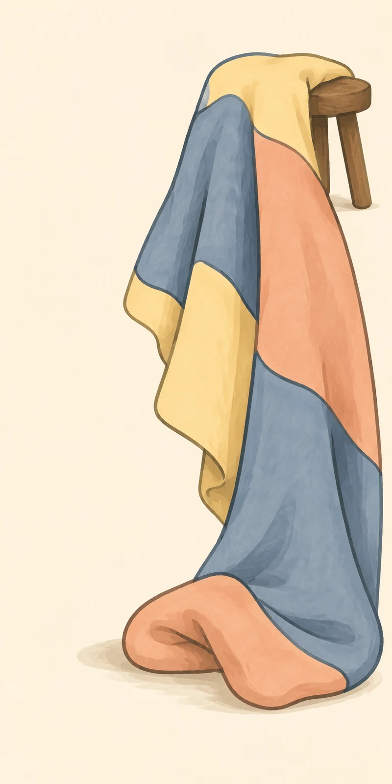 A large patchwork blanket in yellow, dusty blue and peach drapes over a small wooden stool, falling in long folds to the floor against a warm cream background.
