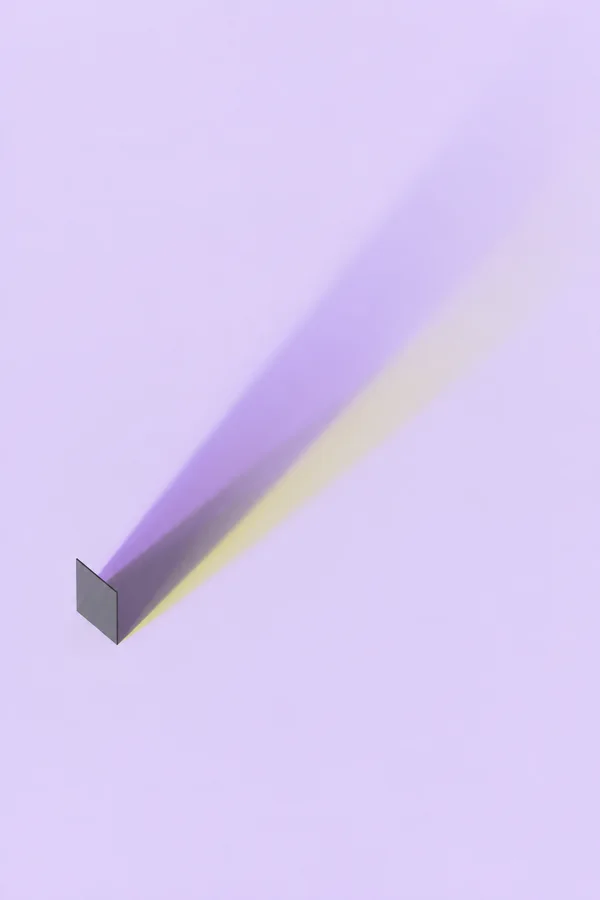 A dark gray quadrilateral stands near the lower left of a pale lilac field, casting a long diagonal shadow toward the upper right with a broad violet band, a…