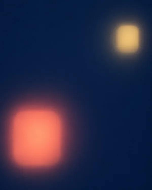 Two softly blurred rounded rectangular light shapes—a large coral glow near the lower-left and a smaller pale-gold glow in the upper-right—float against a deep…