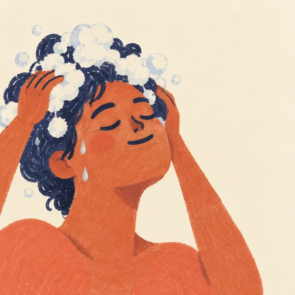 A close-up marker illustration of a person washing their dark indigo hair, eyes closed and hands at the scalp, with cream bubbles around the head against a…