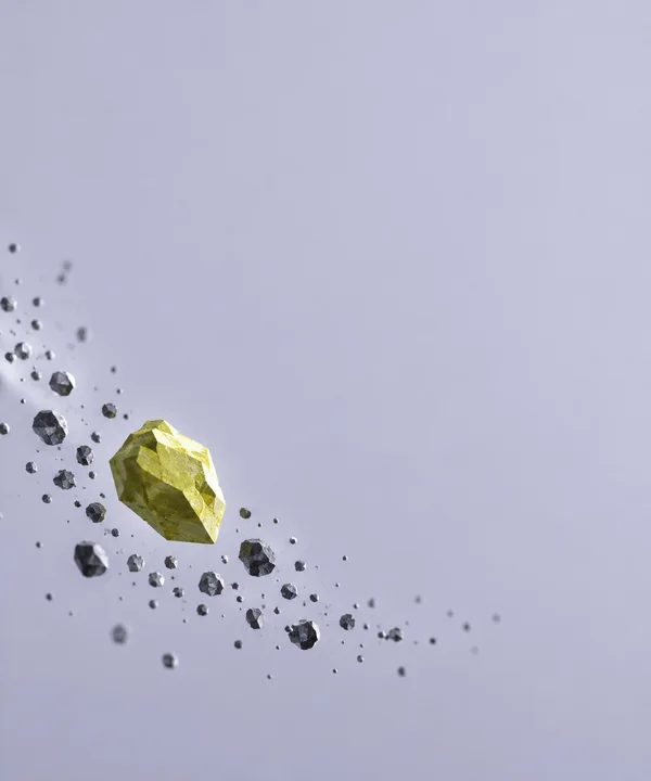 A large angular yellow-green particle floats among smaller faceted graphite-grey particles against a pale lavender field; the particles form a diagonal drift…