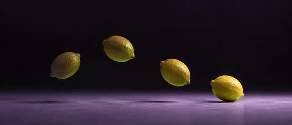 Four successive positions of a yellow lemon move from left to right above a lilac studio floor, ending just at the floor against a dark violet-black background.