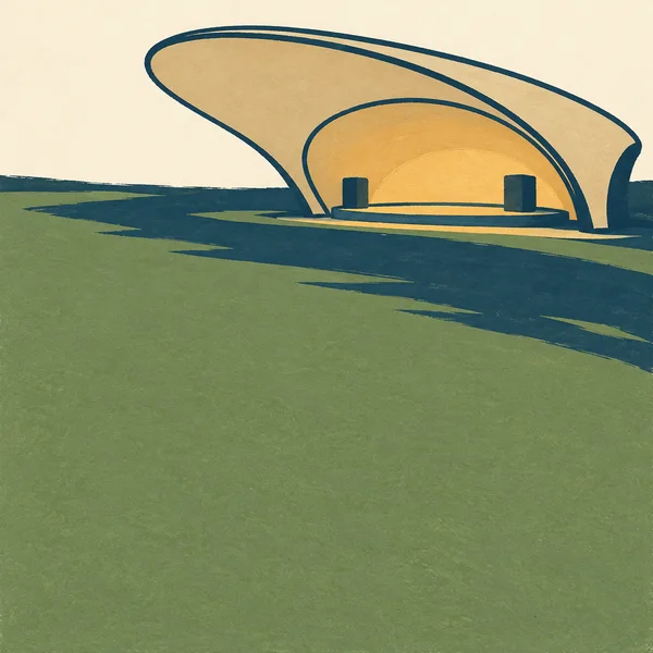 A broad straw-colored bandshell with a small stage and two dark speaker blocks stands beyond an expansive green lawn.