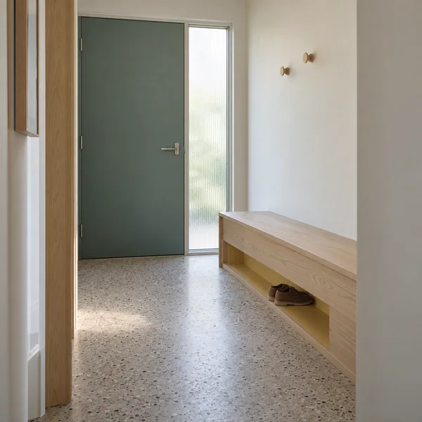 A compact entryway viewed from a hallway, with a closed muted teal door beside a frosted sidelight.