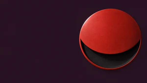 A matte vermilion circular shell sits shifted upward over a recessed near-black circular core, forming a layered abstract sculpture against a deep aubergine…
