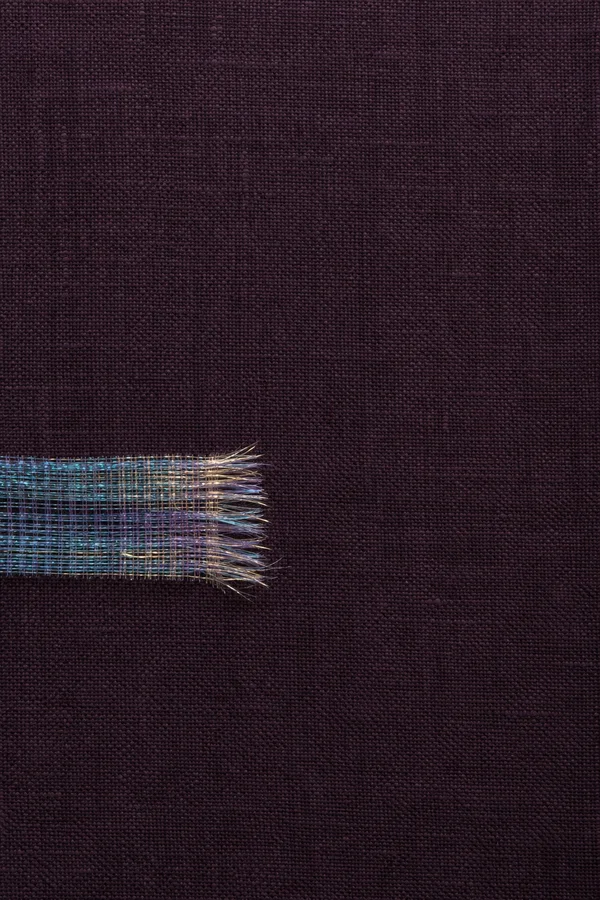 A dark aubergine woven textile fills a portrait frame.