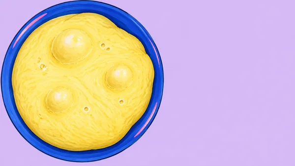 Overhead illustration of a large cobalt-blue bowl filled nearly to the rim with bright yellow dough, showing three rounded raised blisters and several small…