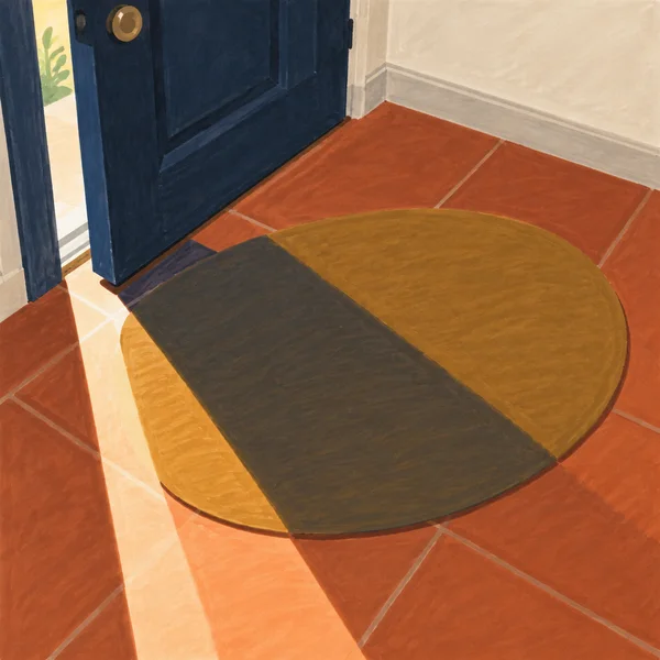 A large ochre oval doormat sits on a terracotta-tiled entryway floor beneath a broad midnight-blue door left ajar.