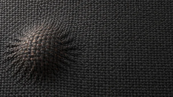 A charcoal woven textile fills the frame, with a raised, puckered mound near the lower-left area and a few muted copper-coloured fibres across its crown; the…