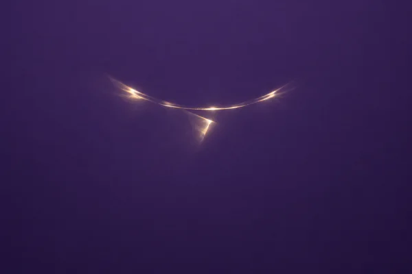 A slender warm gold-white curved light reflection and a small tilted flare sit above the centre of a deep violet field, with broad empty space around them.
