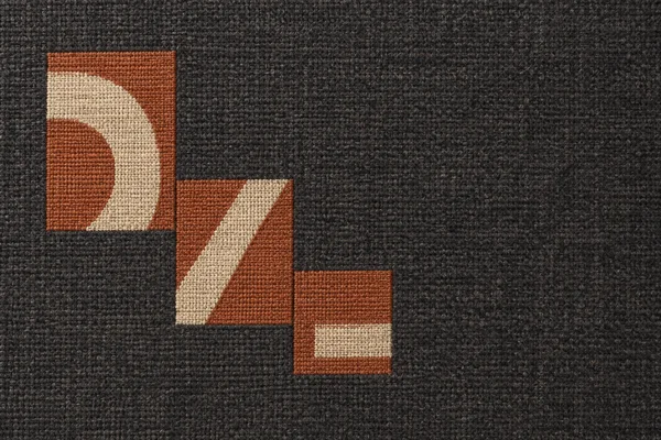 Overhead view of a charcoal woven textile with three terracotta rectangular zones descending diagonally across the left side.
