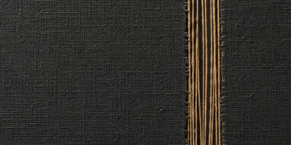 A charcoal woven textile fills the frame, interrupted near the right third by a vertical opening with parallel ochre threads exposed against a dark recess.