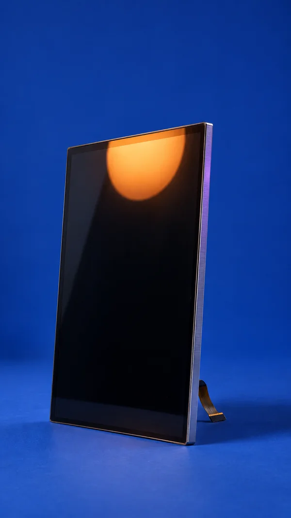 A glossy, nearly black rectangular display panel stands at a three-quarter angle on a cobalt-blue floor against a matching seamless background.