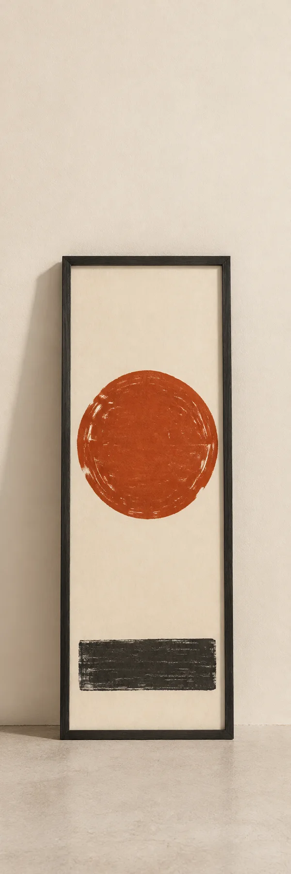 A tall charcoal frame stands on a pale floor against an ivory wall, displaying a rust-red circle above a charcoal block on cream paper.