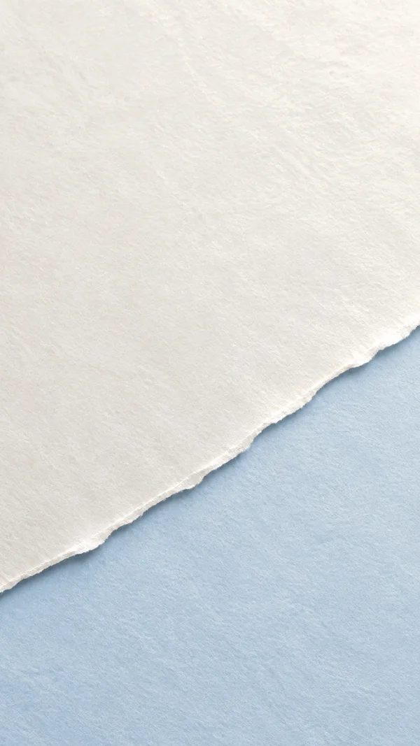 A large warm pearl-white paper sheet fills the upper portion of a vertical composition, with a rough diagonal torn edge revealing pale ice-blue paper below.