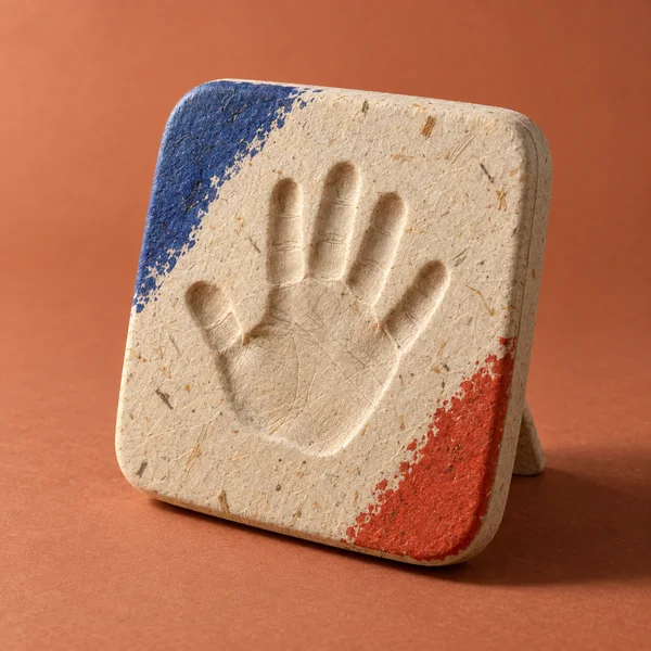 A rounded ivory fiber-textured plaque stands at a slight backward tilt on a molded rear foot against a terracotta studio background.