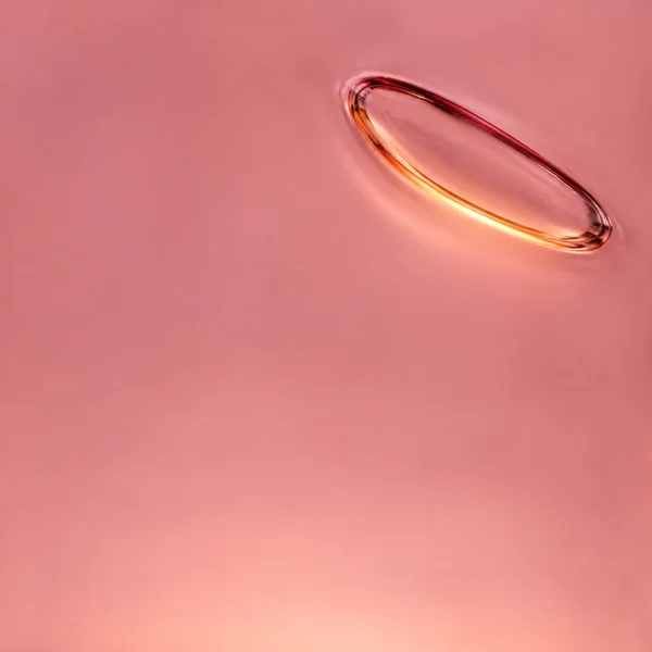 A large tilted oval glass inclusion with dark raspberry and glowing apricot edges sits in the upper-right of a smooth dusty-pink field.