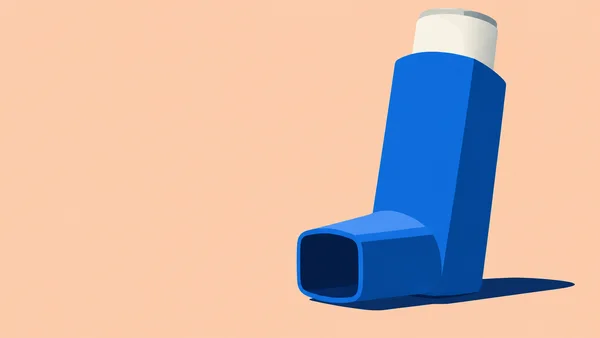 A large cobalt-blue asthma inhaler stands upright on the right against a pale apricot background, with its mouthpiece projecting left, a dark opening, an ivory…