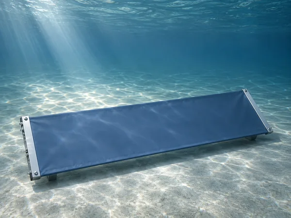 A blank slate-blue rectangular banner stretched between brushed silver rails rests diagonally above a pale, rippled tank floor underwater.