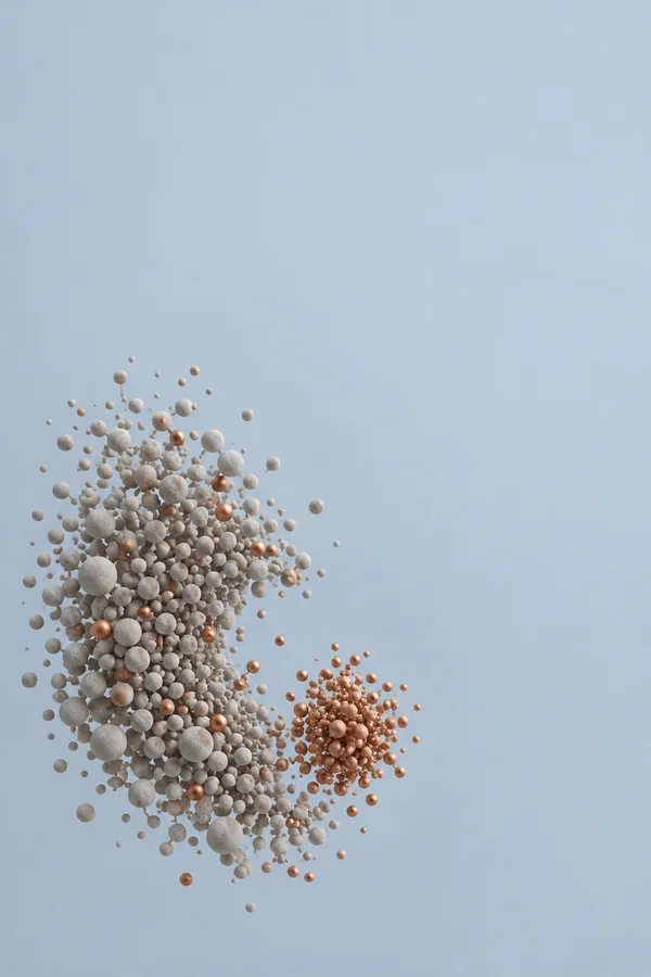 A large irregular cluster of pale warm-grey spheres fills the lower-left area, with copper-colored spheres mixed through it and a smaller copper cluster beside…
