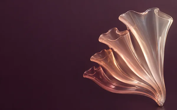A fan of connected translucent peach glass flutes spreads from a narrow base against a smooth deep-plum background, with bright apricot highlights and broad…
