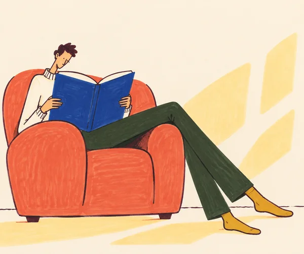 A lanky figure lounges in a wide coral armchair while reading an oversized open cobalt-blue book.