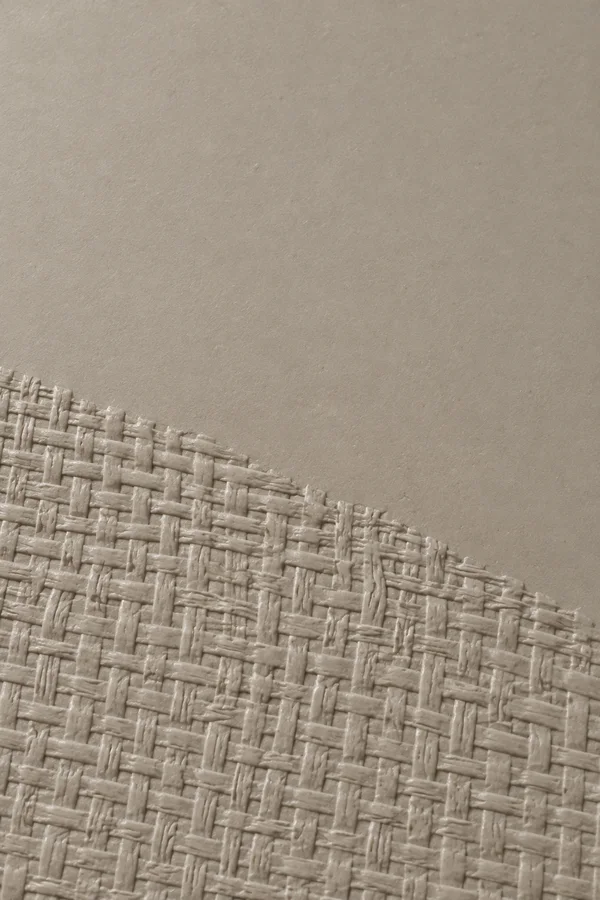A warm grey matte surface with a raised-looking woven texture covering the lower area on a diagonal, beneath a broad smooth upper field.