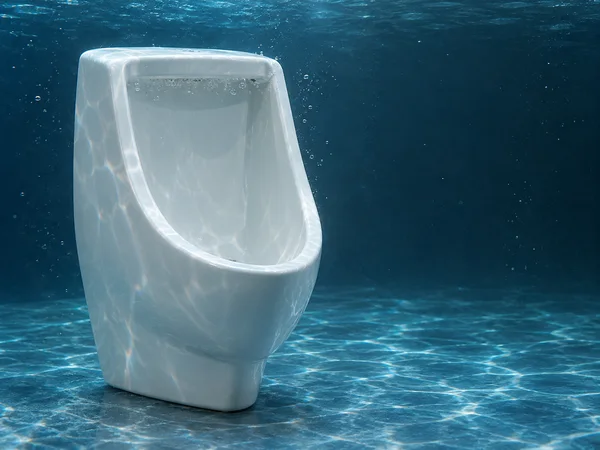 A white ceramic urinal stands upright underwater on a rippled blue tank floor, with bright caustic patterns across its bowl and open dark-blue water to the…