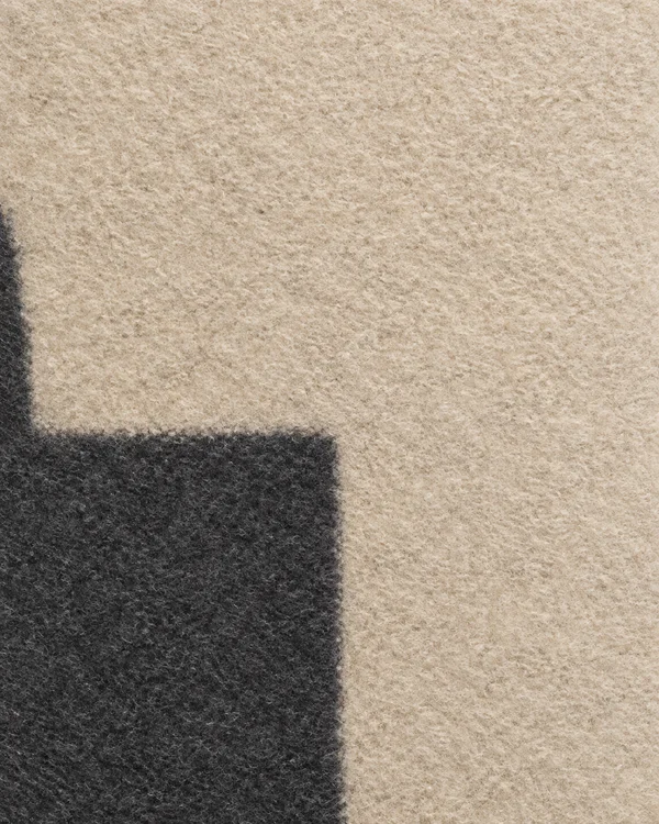 A portrait abstract composition of textured oatmeal and charcoal felt-like fields, with a large charcoal area across the lower left and open oatmeal space…