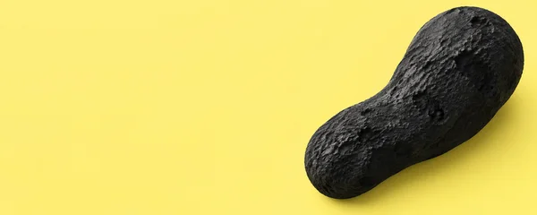 A rough charcoal-black, elongated organic form lies diagonally across the right side of a bright yellow field, with broad pits and granular raised texture; the…