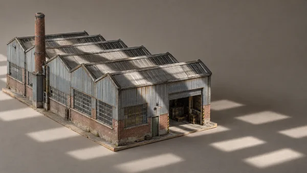 A detailed miniature factory model with a sawtooth roof, corrugated metal walls, brick chimney and open loading bay sits on a thin plywood base against a…