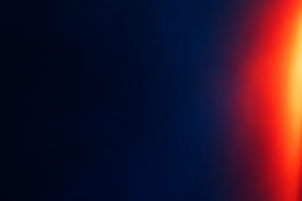 An abstract light-leak composition with a smooth, dark indigo field and a broad vertical red-orange flare cropped along the right edge.