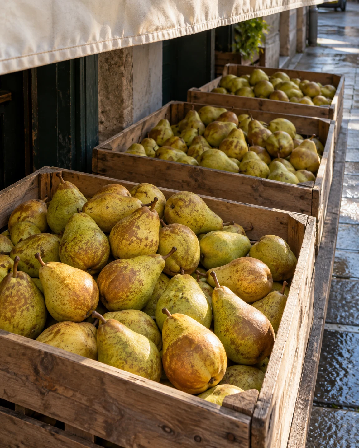 Three wooden crates of yellow-green pears recede along an outdoor stall counter beneath a pale canvas awning.