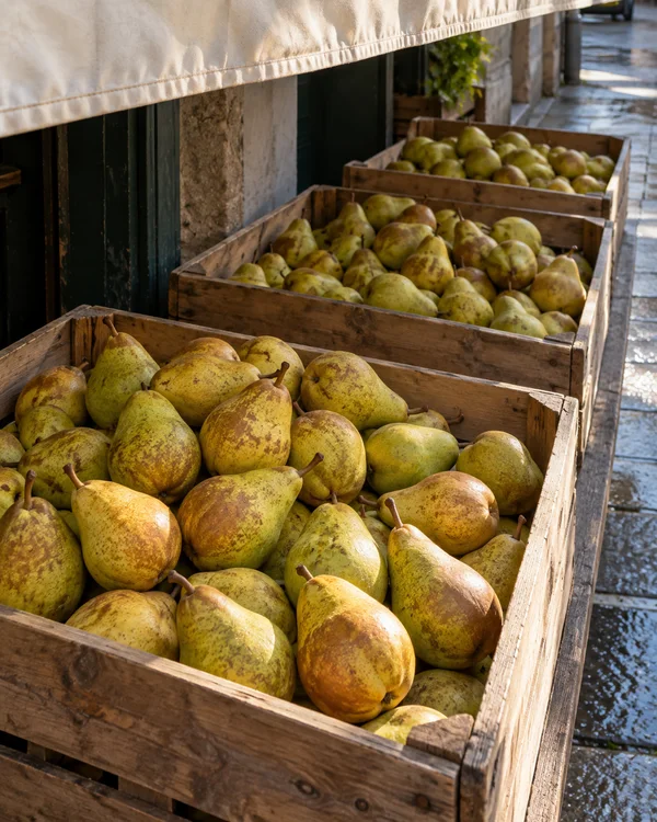 Three wooden crates of yellow-green pears recede along an outdoor stall counter beneath a pale canvas awning.