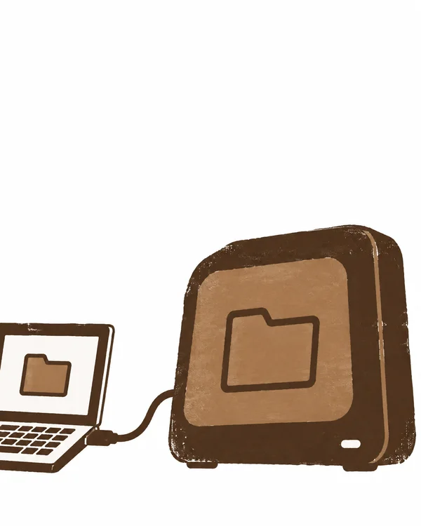A large brown external backup drive with a folder symbol sits beside a cropped open laptop showing a matching folder symbol; a short curved cable connects them…