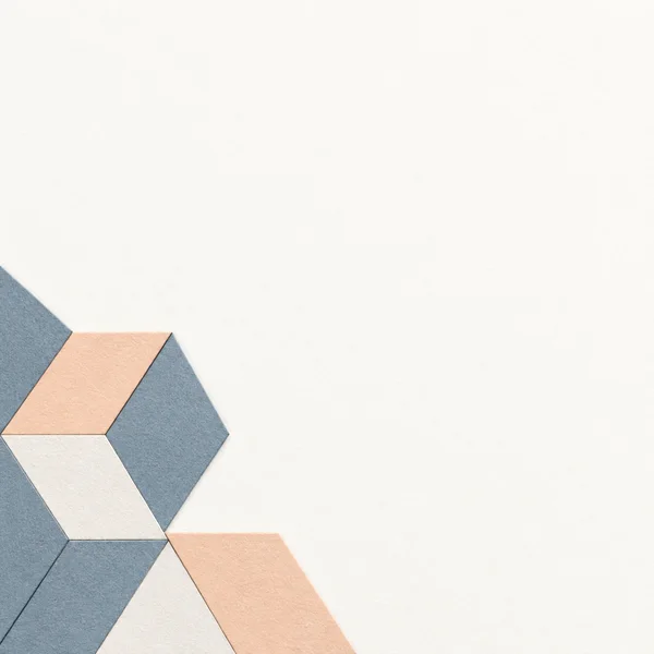 A small arrangement of blue-grey, pale apricot, and near-white textured geometric tiles enters from the left and bottom edges against a large warm-white…
