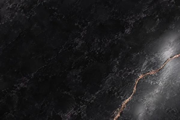 A glossy graphite-black stone surface with violet-grey mineral veining, a copper-toned irregular seam running from the lower edge toward the right edge, and a…