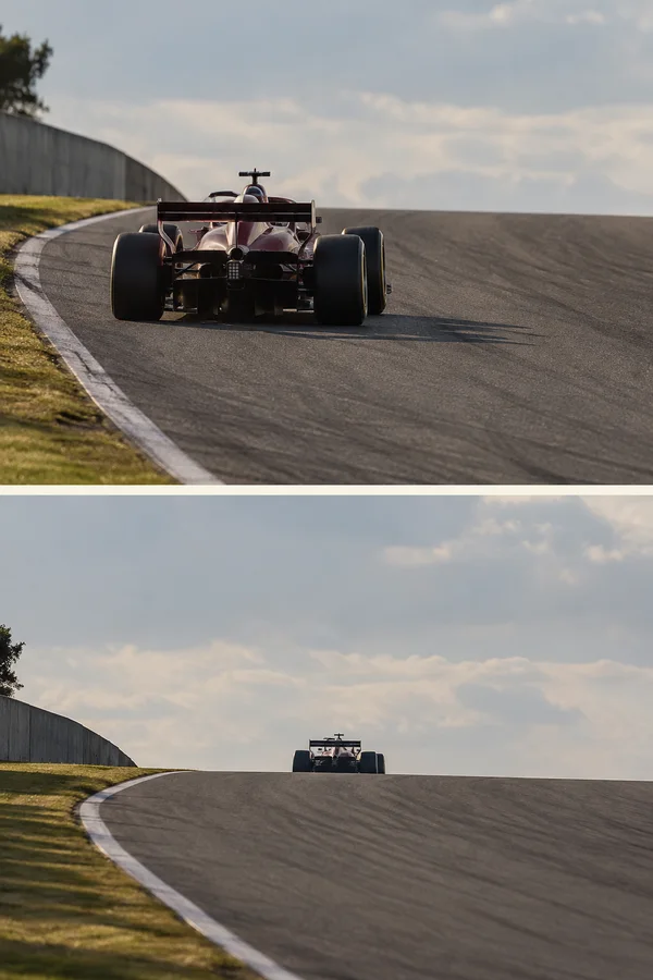A dark aubergine single-seat race car with a pale center stripe is seen from behind on a dry uphill circuit.