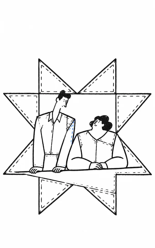 A tall, narrow person and a shorter, broad person lean together behind a white worktable, framed by a large angular star-shaped patchwork motif with dashed…