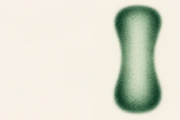 A tall, hourglass-like jade-green particle form with rounded ends and a pinched waist sits on the right side of a warm off-white field, leaving most of the…