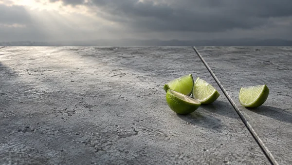 Three cut lime pieces are gathered on a weathered concrete terrace, with a fourth piece set apart across a diagonal joint; a cloudy sky and distant dark…