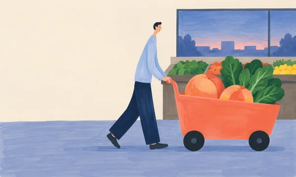 A shopper in a pale blue shirt and dark navy trousers pushes a large coral grocery cart filled with two peaches and leafy greens across a blue-toned…