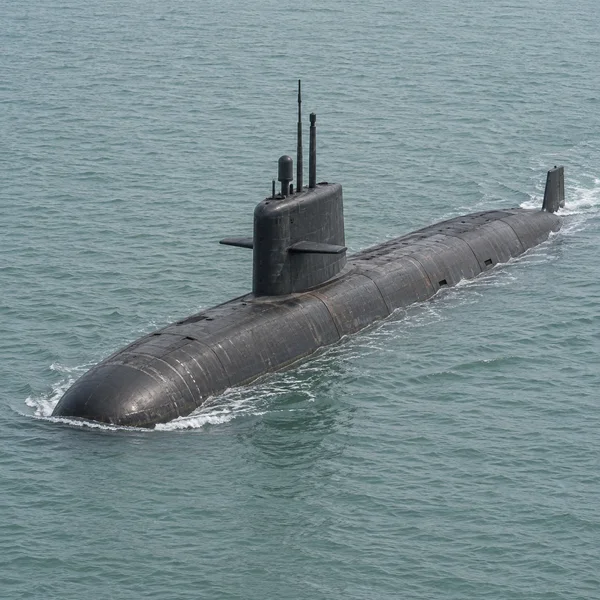 A large charcoal submarine travels diagonally across pale sea-green water, with its rounded bow in the lower left, raised sail near the center, and wake…